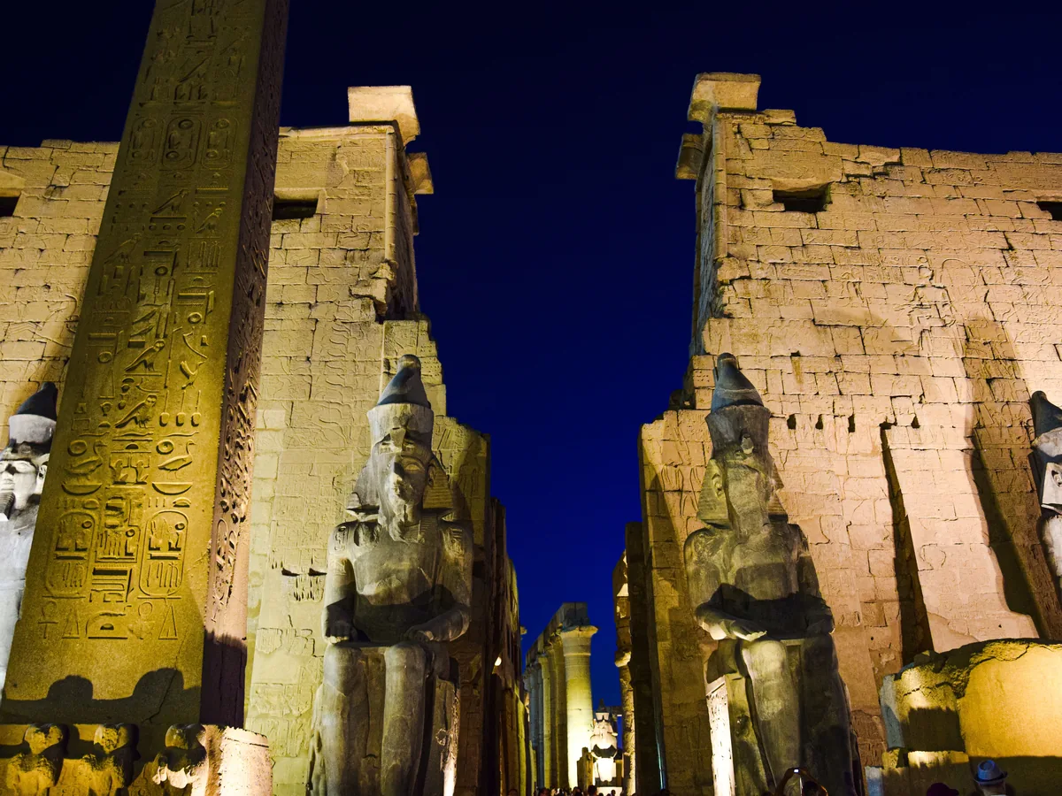 夜にライトアップされたルクソール神殿と、その古代の像やヒエログリフ